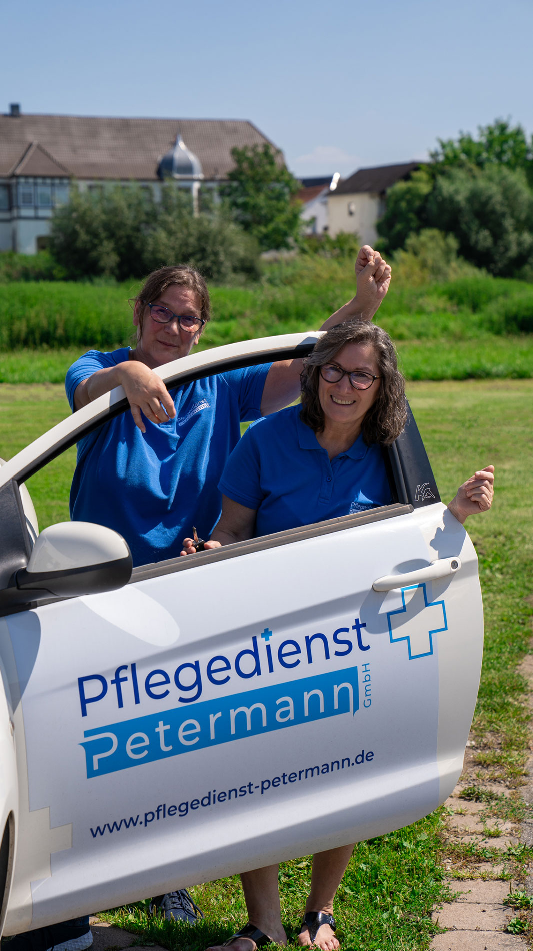 Zwei Mitarbeiterinnen des Pflegedienstes Petermann stehen lachend neben einem Fahrzeug – Symbol für persönliche Pflege vor Ort.