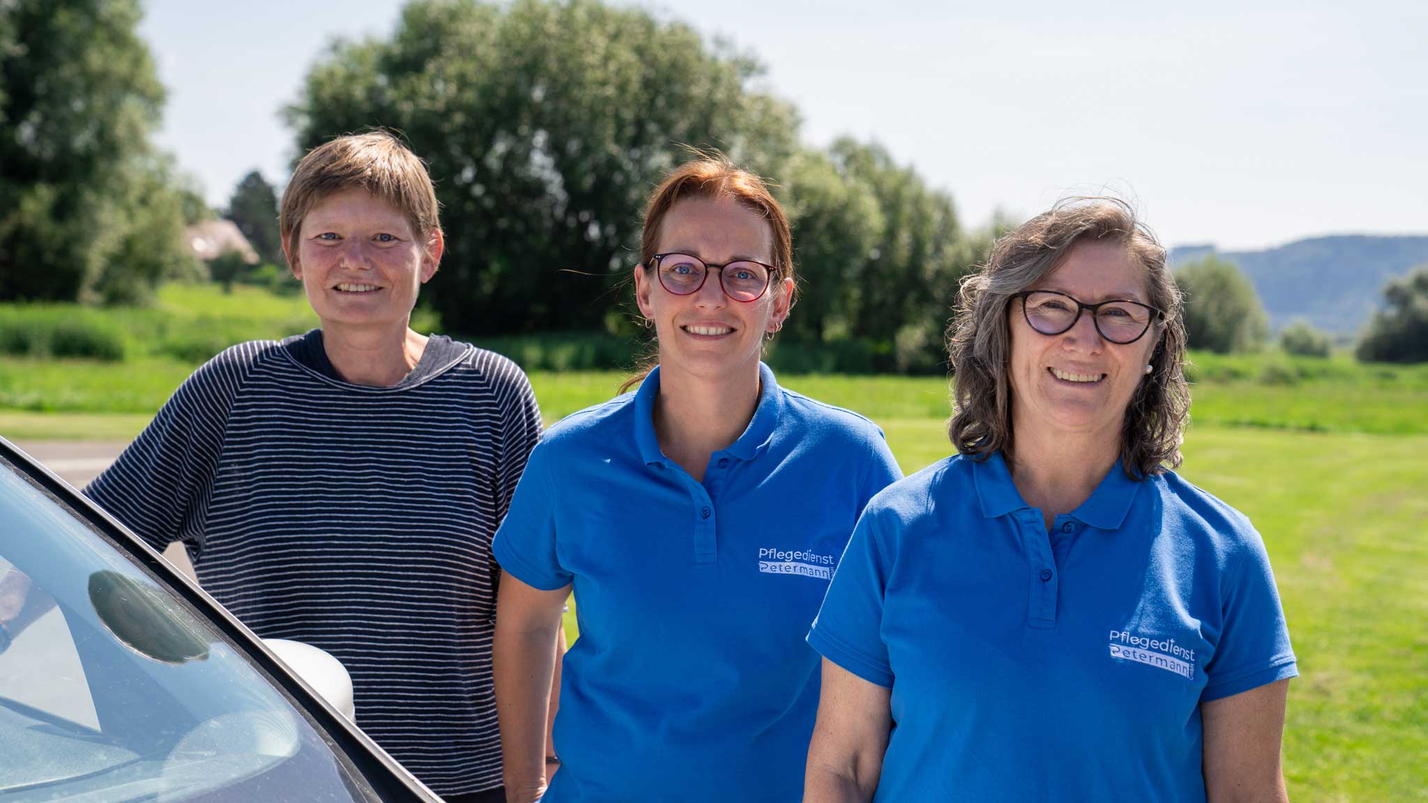Drei Mitarbeitende des Pflegedienst Petermann bei sonnigem Wetter als Teamfoto für die Personalgewinnung
